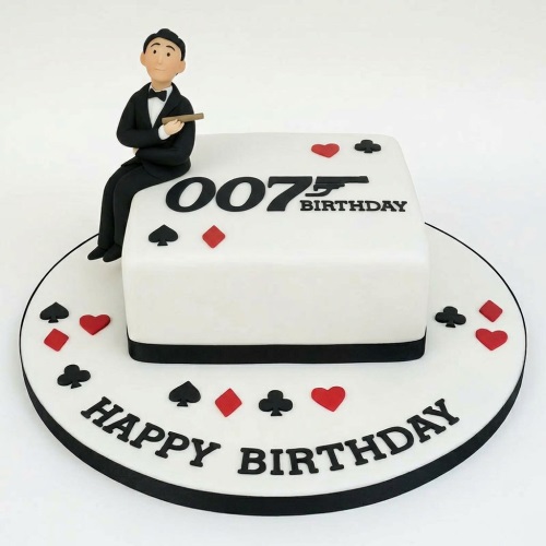 White square 007 James Bond birthday cake with a man in a tuxedo and card suits.