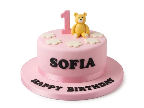 Pink round cake with a yellow teddy bear, pink number one topper, white flowers, and a pink ribbon.