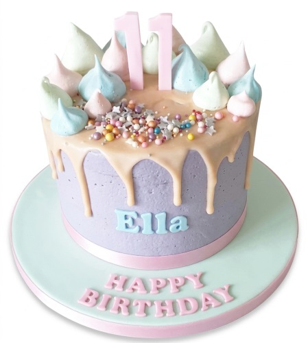 Round lavender drip birthday cake with pastel meringues, sprinkles, and a custom age topper.