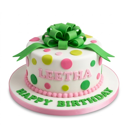 White round cake with pink, green, yellow polka dots and a large green fondant bow on top.