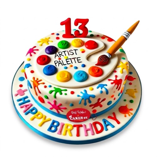 Two-tier white birthday cake with an artist's palette, paintbrush, colourful paint splatters, and a custom age topper.