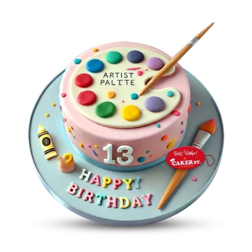 Round pink birthday cake with an artist's palette, paintbrush, crayon, and custom age topper.