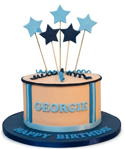 Round peach birthday cake with blue and navy star toppers, blue ribbons, and a custom message.