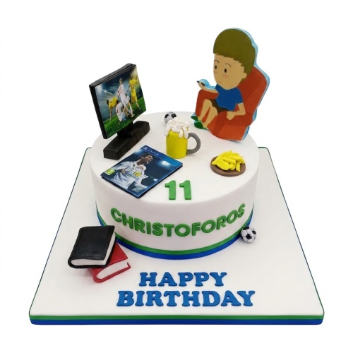 White single-tier birthday cake with gaming and football theme, featuring a character watching TV, a PS4 game, fries, and books.