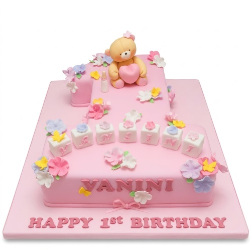 Pink number one shaped cake with teddy bear, baby bottle, flowers, and custom name blocks.
