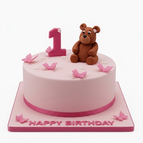 Pink round 1st birthday cake with a brown teddy bear, pink number one, and pink butterflies.