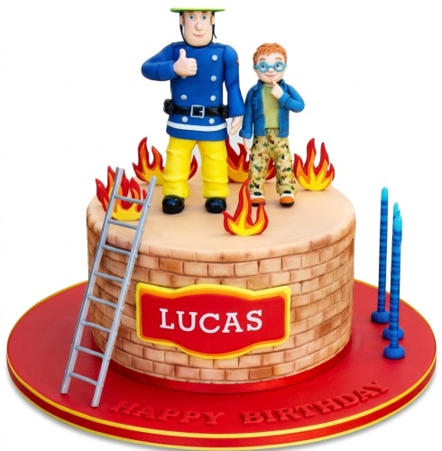 Round Fireman Sam birthday cake with character figurines, flame decorations, ladder, and personalised name plaque.