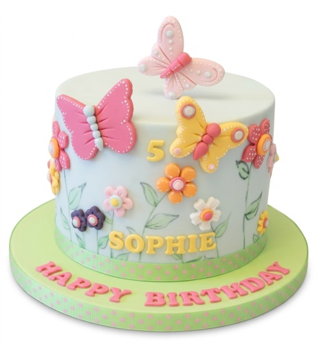Round white cake with pink and yellow 3D butterflies, colourful sugar flowers, and green leaves.