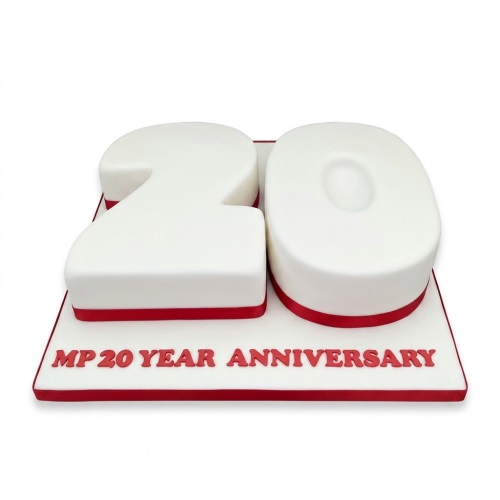 White number 20 cake with red ribbon and 'MP 20 YEAR ANNIVERSARY' text on a white board.