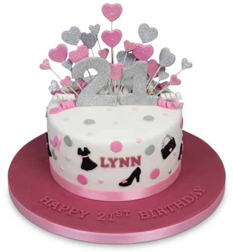 White round cake with black dress, handbag, high heel shoe decorations, pink and silver polka dots, and glittery pink and silver heart toppers.