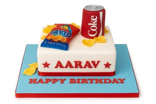 White square birthday cake with red and blue accents, topped with a red soda can and a blue crisps bag.