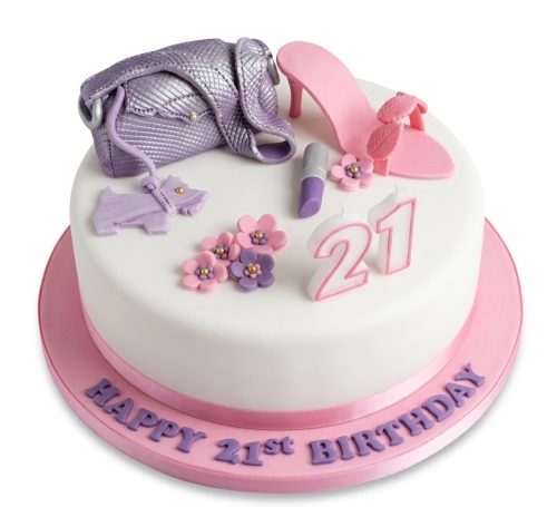 White round birthday cake decorated with a purple handbag, pink high-heel shoe, lipstick, small pink and purple flowers, and number candles.