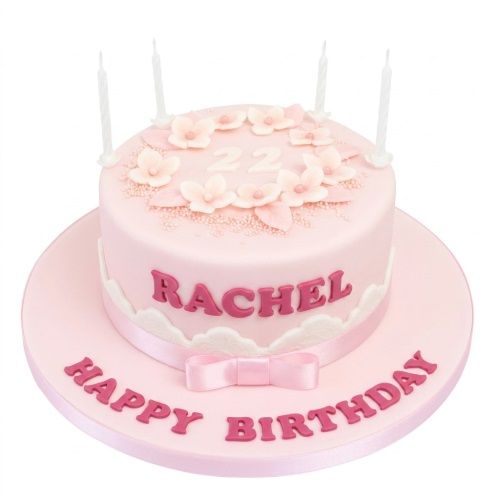 Pink round birthday cake with light pink sugar flowers, white scalloped trim, pink ribbon, and custom age topper.