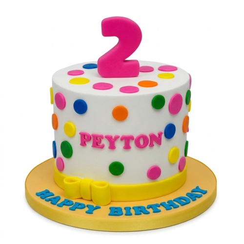 Round white birthday cake with colourful polka dots, yellow ribbon, and a pink custom age topper.