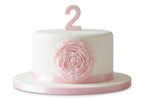 White round cake with large pink sugar flower, pink ribbon, and a pink number two age topper.