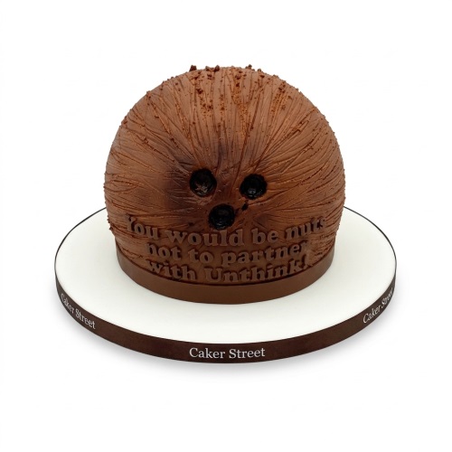 Round brown Chewbacca-themed birthday cake with textured fur and black eyes on a white cake board.
