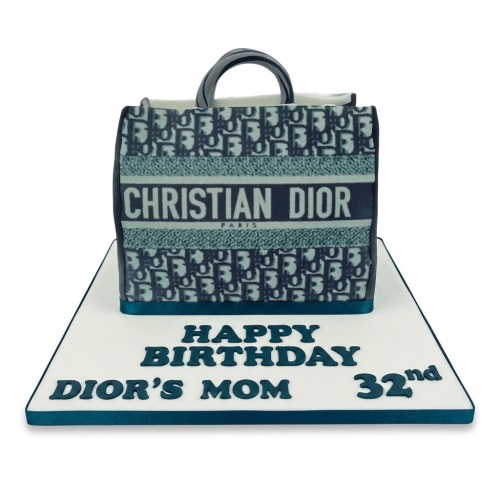 Christian Dior handbag shaped birthday cake with custom message on white board.