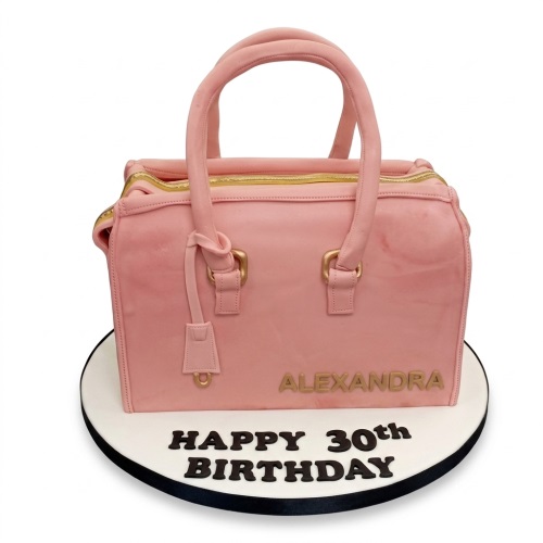 Pink handbag shaped birthday cake with gold details and custom age message