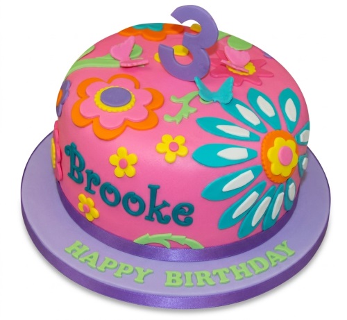 Pink dome cake with colourful flowers, butterflies, and a number three topper.