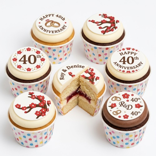 A selection of 40th Anniversary cupcakes with white and chocolate frosting, decorated with ruby blossom branches, wedding rings, and "Happy 40th Anniversary" toppers, some with personalised names.
