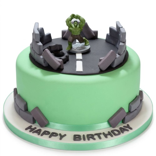 Green Hulk birthday cake with superhero figure, road, and grey debris decorations.