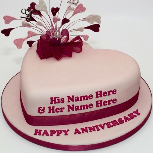 Heart-shaped anniversary cake with pink fondant, burgundy ribbon, and glitter heart toppers, with space for custom names and message.