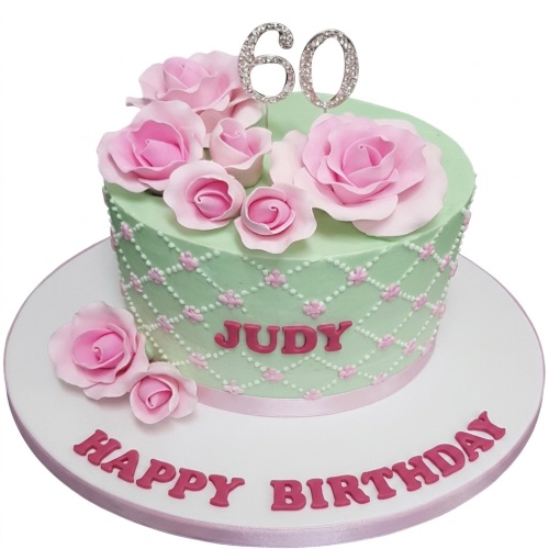 Round mint green birthday cake with pink sugar roses, lattice piping, and a custom age topper.