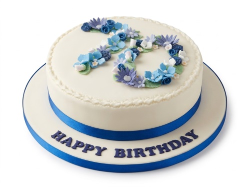 Round cream birthday cake with blue and purple sugar flowers forming a custom age, royal blue ribbon, and 'Happy Birthday' message.