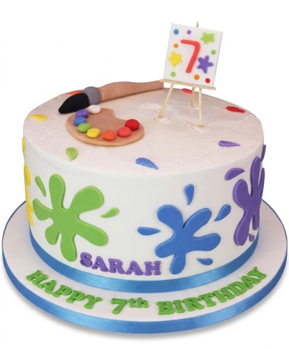 White round cake with colourful paint splatters, an artist's palette, paintbrush, and an easel with a number topper.