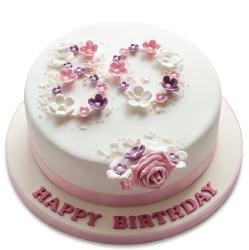 Round white birthday cake with pink and purple sugar flowers, custom age topper, and 'Happy Birthday' message.