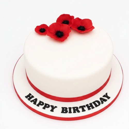 White round birthday cake with red poppy flowers and a red ribbon, with "Happy Birthday" written on the board.