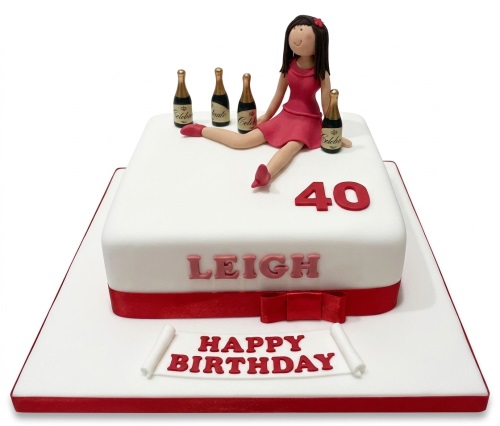White square birthday cake with female figurine, champagne bottles, custom age, and personalised name.