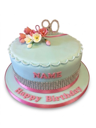 Mint green round birthday cake with pink and white sugar flowers, a sparkling custom age topper, and rhinestone ribbon detail.