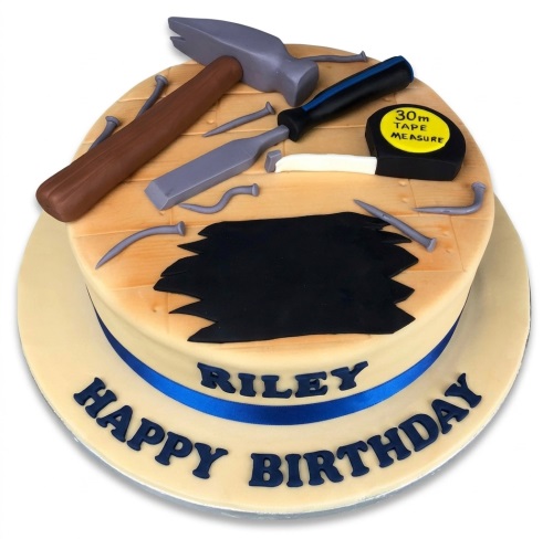 Round construction theme birthday cake with edible hammer, chisel, screwdriver, tape measure, and nails on a wooden plank design.