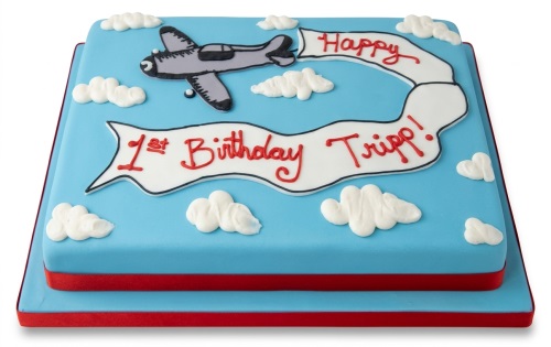 Two-tier square blue birthday cake with a grey aeroplane, white clouds, and a red custom message banner.