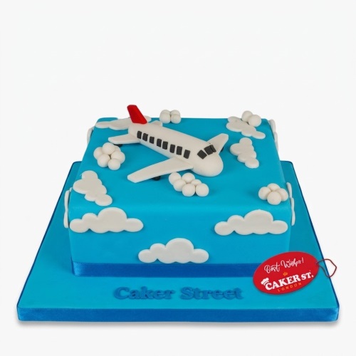 Blue square cake with a white airplane topper and white clouds for a birthday celebration.