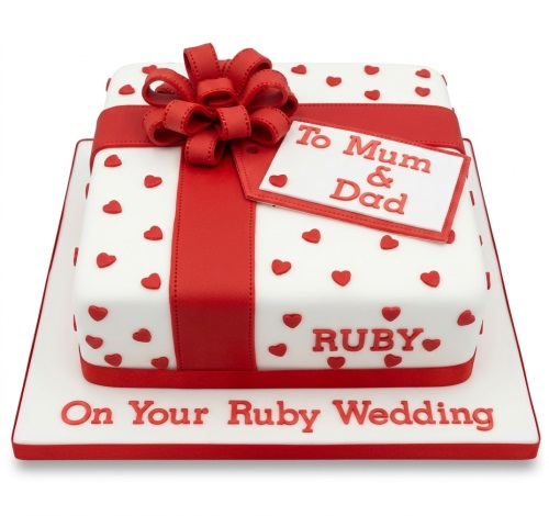 White square gift box cake with red ribbon, bow, and scattered hearts, featuring 'On Your Ruby Wedding' message.