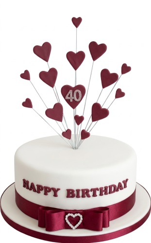 White round birthday cake with deep red heart spray topper and custom age.