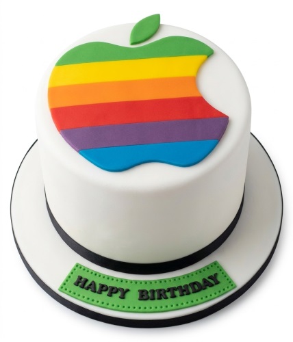 Round white birthday cake with a large rainbow Apple logo on top and a green 'Happy Birthday' plaque.