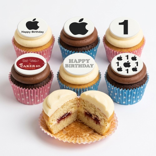 Assortment of vanilla and chocolate cupcakes with white toppers featuring black Apple logos and 'Happy Birthday' messages, in pink and blue polka dot cases.