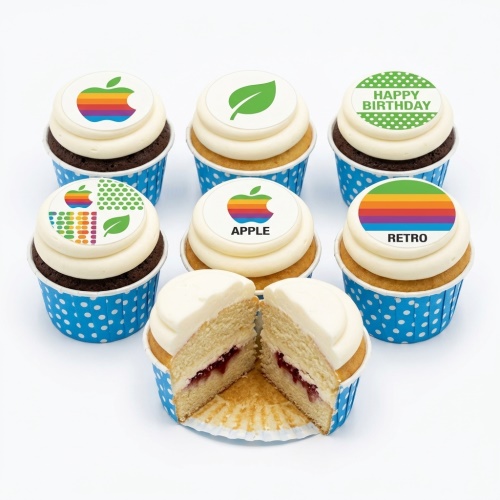Cupcakes with white frosting, blue polka dot cases, and edible toppers featuring retro Apple logos, rainbow stripes, a green leaf, and "Happy Birthday" text.