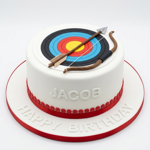 White round birthday cake with an archery target, bow, and arrow on top, with a red ribbon and custom name.