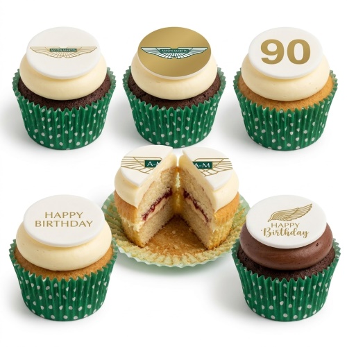 Six Aston Martin themed birthday cupcakes with white and gold logos, 'Happy Birthday' message, and a custom age topper in green polka dot wrappers.