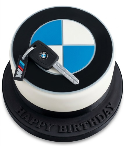 Round white and black BMW logo birthday cake with an edible car key on top and "Happy Birthday" on the board.