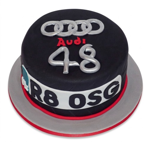 Round black Audi car theme birthday cake with silver logo, red text, and custom age '48' and 'R8 OSG' message.