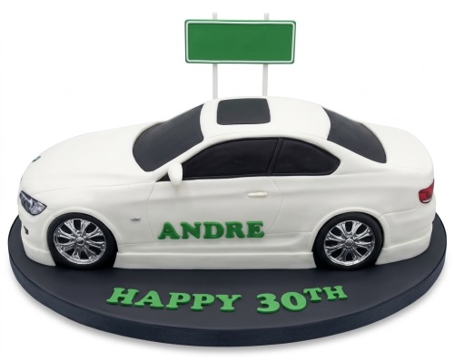White 3D sculpted sports car birthday cake with green custom name and age on black board.