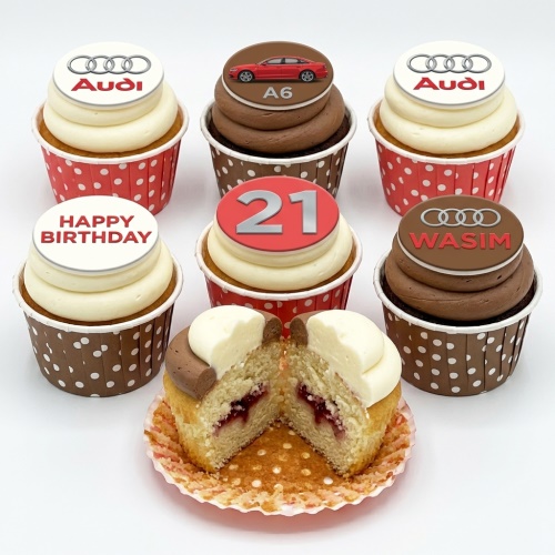 Six Audi themed birthday cupcakes with car and logo toppers, one with custom age 21, and one with "Happy Birthday" message.