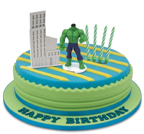 Round two-tier Hulk birthday cake with building topper, Hulk figurine, and candles.