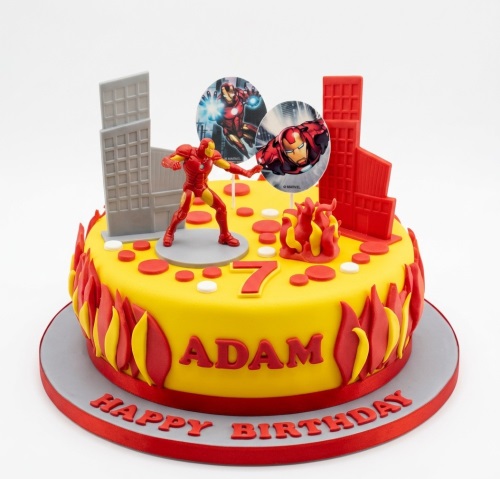 Yellow Iron Man birthday cake with figurine, building decorations, and custom age topper.