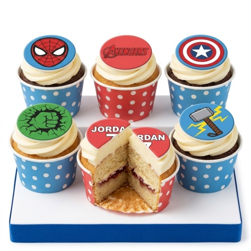 Six cupcakes with white frosting and edible superhero toppers including Spider-Man, Avengers logo, Captain America shield, Hulk fist, and Thor's hammer.
